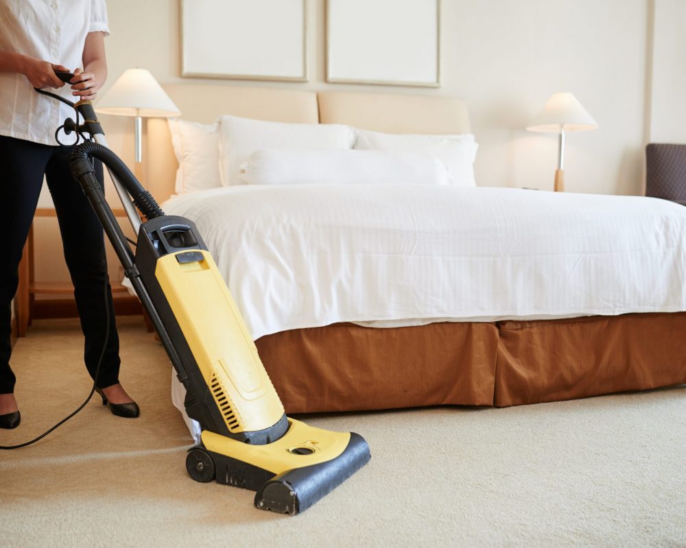 Cropped image of maid cleaning carpet in hotel room